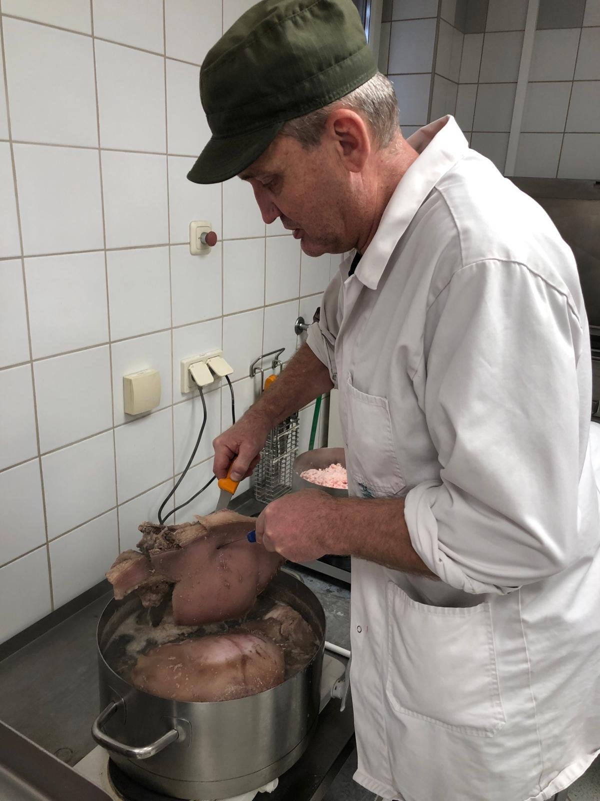 ein Mann beim Kochen von Fleisch in Suppentopf